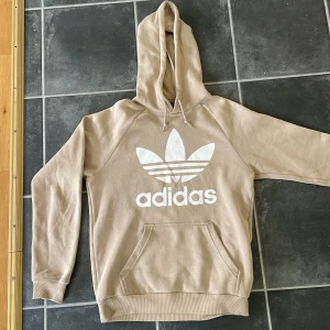 Adidas hoodie - Snygg beige Adidas-hoodie. Säljs pga kommer inte till användning längre. I mycket bra skick. Köpt i Spanien för cirka 600-700 kr 2018. Därav svår att hitta på nätet eller annanstans. Är i storlek S men är lite stor i storlek så passar M Säljs för 149 kr. 