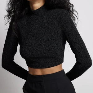 Croppad glittrig topp - Superfin & helt oanvänd svartglittrig topp med halvpolo & axelvaddar från NA-KD. Som ny! 🖤✨ Slutsåld i S på NA-KD.