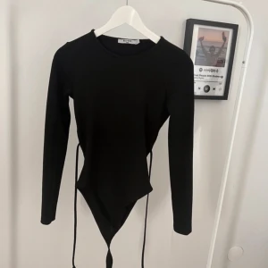 Långärmad med öppen rygg - En svart långärmad body från NA-KD med öppen rygg. Använd fåtal gånger, den är i mycket bra skick!