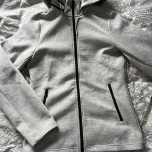 Hoodie J.Lindeberg stl S - Jättefin ljusgrå hoodie från J.Lindeberg i stl S. I princip oanvänd med väldigt fina detaljer och figursydd fit! Köparen betalar frakt💫