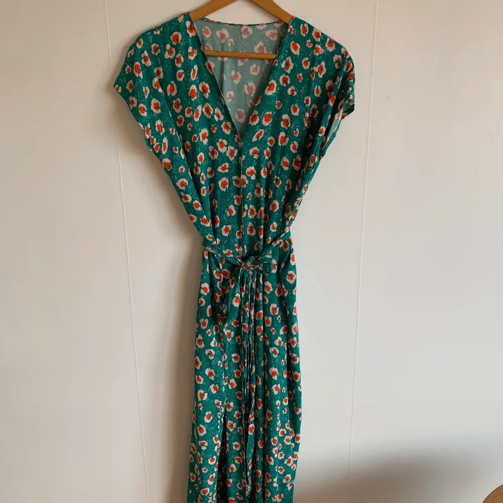 Blommig långklänning. Med skärp och knappar framtill i viskos. . Mekot.