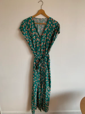 Blommig klänning  - Blommig långklänning. Med skärp och knappar framtill i viskos. 