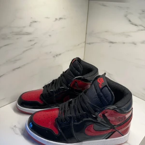 Air Jordan 1 Retro High OG 'Patent Bred' - Jordans skor knappt använda, fel fria o fläckfria. Använda en gång med försiktighet. Pojken fick dem som present från släktingar i USA! 