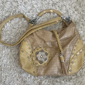 handväska  - söt handväska med metalldetaljer i ljusgula/beigea färger, lite defekter vid handtaget, annars bra skick. 