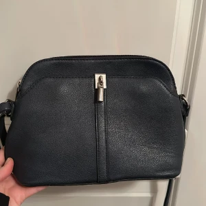 Axelremsväska  - Snygg axelremsväska i marinblått. I bra skick utan direkta slitningar.💙 Uppskattningsvis är den 22cm lång och 20 bred