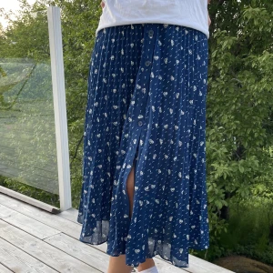 Långkjol &OtherStories - Blå långkjol från Stories i blått tyg med vita blommor. Använd ett fåtal gånger. Jag är en storlek S/M så sitter ganska högt i midjan på mig. Men för dig som bruakr köpa 34 kommer den sitta lägre och bli längre!