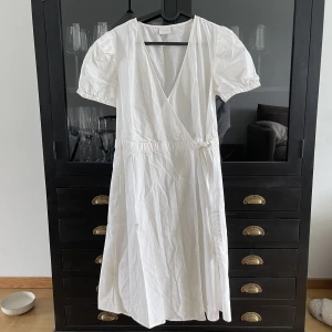 Omlott i skjortmaterial - Vit omlottklänning med knytning från VILA.  Använd 2 gånger. Mycket bra skick. 