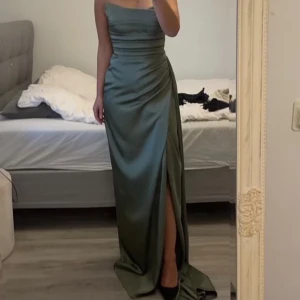 Bal/bröllops klänning - En fin bal/bröllops klänning i militärgrön satin. Använd 2 gånger. Storlek stor 34a-36 men mer en 36a. 