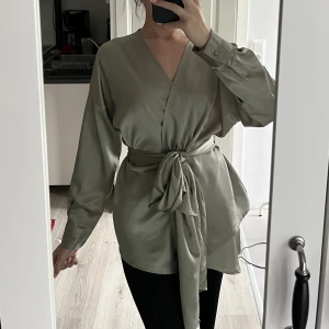 Omlottblus strl 34 - Använd vid endast 2 tillfällen. Jag har använt en säkerhetsnål för att säkra fast toppen och minska urringningen, vilket har orsakat mindre skador på plagget vid bröstet. Det går dock att dölja med säkerhetsnål. Jag upplever den som stor i storleken.