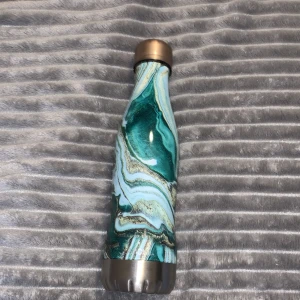 Termosflaska - En vattenflaska som håller kyla och värme. Är ett samarbete med GLACIAL och Ideal of sweden. Den är grön ”marmor”. Den rymmer 400ml