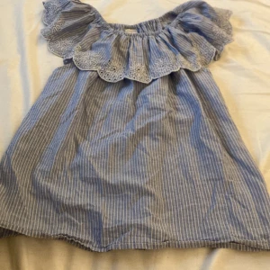 Blå blus🩵 - En blå/vit randig blus med en volang upptill och är stretchig där uppe storlek 146/152 och är liten  storleken 