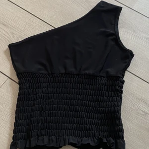Svart topp - Så så fin svart one shoulder topp. Aldrig använt ❤️ 70kr frakten inräknad i priset. Tryck inte på köp nu, skriv först ❤️