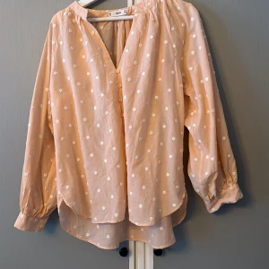 Blus - Aprikos färgad blus med vita prickar . Nyskick,knappt aldrig använd. (Frakt tillkommer)