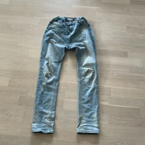 Jeans - Ljusblåa jeans, två pyttesmå rosa fläckar på ena benet