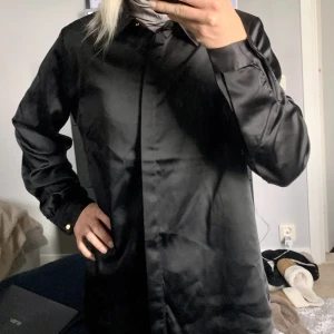Skjorta  - Svart skjorta/blus i satin från Vila. Mkt bra skick. Sååå fin, lite kraftigare tyg som ger snyggt fall och lyxig känsla. Stl 40 men passar allt från 36-42 beroende på hur man vill ha den. Är normalt en 34/36 men har haft denna ”oversize”. 