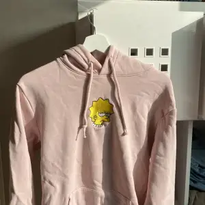 Rosa Simpsons hoodie med tryck på Lisa. Inga tydliga defekter. Passar M.