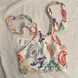 Mönstrig halter topp - Halter crop topp i linnetyg från Zara! Helt oanvänd med lapp kvar (org. pris 299kr), fint färgglatt mönster på med resår där bak så den stretchar ut💗🙌 Skulle därför även kunna passa M.