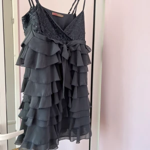 Festklänning - Mörkgrå festklänning med paljetter och volanger, superbra skick och reglerbara band! Dragkedja på sidan💕