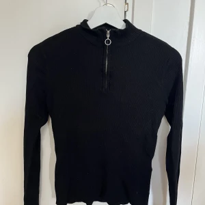 Svart ribbad tröja - En ribbad svart tröja med dragkedja, använd men i bra skick. 