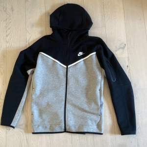 Svart grå Nike tech fleece tröja. Köpt 2022 i december och använd få gånger. Mycket bra skick 9/10. Köpt från footlocker för 1349kr och har storlek Large. Den är numera ganska svår att få tag på eftersom det är förra årsmodellen.