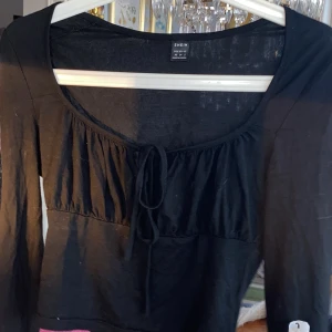 Topp - Säljer en svart långärmad tröja med knytning vid brösten💖
