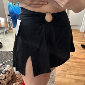 Snygg kjol - Snygg kjol med fin detalj på framsidan. Dragkedja på sidan och ett otroligt skönt material. Kan användas till vardags och till fest. Mer info på sista bilden. Jag är 172cm. Är helt oanvänd! KOLLA GÄRNA IN MINA ANDRA ANONSER, DET MESTA ÄR HELT OANVÄNT 🥰