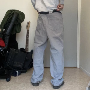 Baggy Acne Studios byxor - Superfina baggy byxor från acne studios med pressveck på framsidan för en speciell passform, men dem har börjat lossna och därför priset, jätteenkelt att laga, ljusgråa, dm för fler bilder midjevidd 47cm, benöppning 27 cm,  Ytterbenslängd 112cm