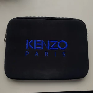 Kenzo datorfodral  - Säljer mitt fina kenzo datorfodral pga flytt! Passar vanlig macbook (tror 13” är den vanliga) och får samtidigt plats med bok/anteckningsblock. Enstaka tecken på användning därav priset. Nypris: ca 1600 tror jag. Hör av dig vid frågor🌸🫶🏼