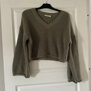 Stickad tröja  - En olivgrön stickad tröja med vida ärmar.