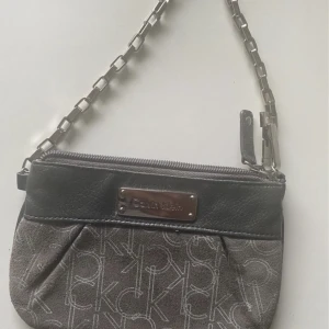 Liten väska från Calvin Klein - Liten väska i nyskick från Calvin Klein. Köpt på outlet i USA för några år sedan. Inte använd.   Mått: 17 cm bredd/längd 11 cm hög