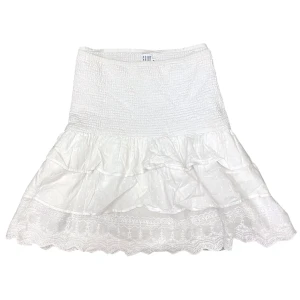 Kortkjol Med Volanger  - Varan kan köpas direkt på vår hemsida, ettmarke.se Märke: Saint Tropez Modell: Kortkjol Färg: Vit Storlek: M enligt lapp. Kan passa fler storlekar då kjolen har resårband. Midja platt rakt över: 37 cm Totallängd (från midjan): Ca 47 cm Skick: Fint skick