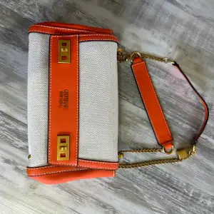 Väska från Guess aldrig använd i orange/beige färg. Längden är 26 vem vidd 8 cm och 16 cm hög. Det går att anpassa Axelsen och använda dem på 2 olika sätt. 