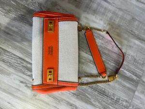 Väska - Väska från Guess aldrig använd i orange/beige färg. Längden är 26 vem vidd 8 cm och 16 cm hög. Det går att anpassa Axelsen och använda dem på 2 olika sätt. 
