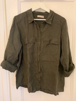 Mörkgrön linneskjorta Rabalder - Mörkgrön linneskjorta ”Helmina” från Rabalder, inköpt hösten 2022 och använd några månader. Fint skick, inget att anmärka på. Strl L, passar S-L.   Nypris 899 kr. Hämtas vid Nobeltorget eller postas mot frakt.