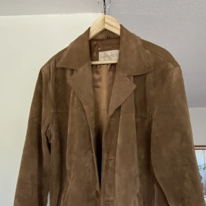 Brun kavaj mocka  - Brun kavaj i mockamaterial. Vintage. Aldrig använd av mig. Bra skick, inga hål eller lösa trådar mm