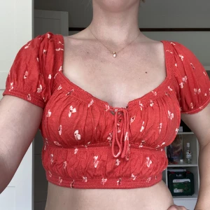 Röd Blus - Starkt röd blus/T-shirt från Urban Outfitters i bomull/linne aktigt material. Köpt för drygt 300 kr och använd ca 15 gånger. Säljer då jag ej använder. Rygg har samma skurning som framsidan fast utan snittet i mitten. 