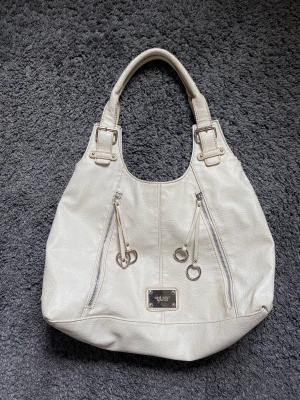 Krämvit handväska  - Krämvit väska i märket Nine West.  Jag har köpt den på sellpy och den är i fint skick men den har aldrig kommit till användning av mig. 