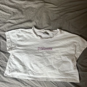 Gymshark topp - Croppad trängings-tshirt från gymshark.  Använd i gott skick, finns en liten fläck nästan längst ner på tröjan som knappt syns. Köparen står för frakten.