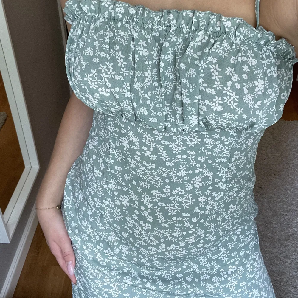 Säljer denna otroliga klänning i en jättefin grön färg med vita blommor. Man knyter axelbanden själv så den går att ändra lite själv, den formar dessutom kroppen så fint! Säljer då jag har så många klänningar redan. Storlek S🤍 säljer för 100kr + frakt. Klänningar.