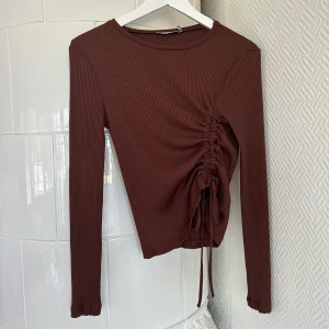 Topp - Ribbad långarmad topp från NA-KD, aldrig använd. Fin detalj med justerbart band! 🤎