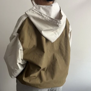 Windbreaker - Vit och khaki Windbreaker med  magficka med dragkedja samt sidofickor. Tål regn och vind bra, inte true to size utan är mycket oversize! Går att dra åt undersidan så den sitter tajtare. Nyskick! 