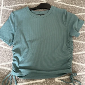 Grön topp från Zara - En fin topp med knyten på sidan där man bestämma hur lång eller kort den ska bli. Bra skick. I strolek L men ganska liten