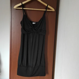 Topp från Gina Tricot - Topp från Gina Tricot i svart färg. I nyskick och oanvänd. Verkar ha ett syfel på en av axelbanden som hamnar uppochner, men inget som påverkar funktionen. Material: 92.5% polyester, 7,5% Elastan.