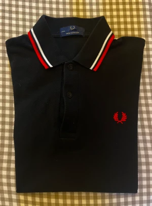 Fred Perry piké  - Stilren svart piké från Fred Perry. Aldrig använd, legat i garderoben. Nypris 800kr.