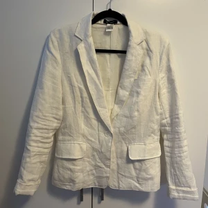 Kavaj 100% linne - Snygg vit kavaj i 100% linne från La Redoute. Bröstficka, axelvaddar, fickor fram och knappar på ärmarna. Storlek 38