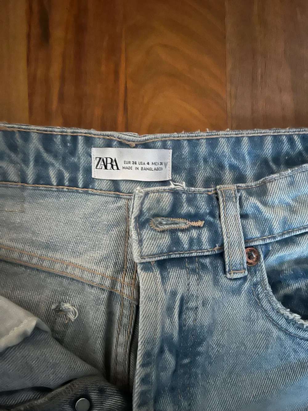 säljer dessa ljusblåa åjeans med hål i straight fit från Zara då de blivit för små för mig. Är i bra skick förutom att de har en liten färg prick som inte går bort (skicka för bild). Är 157cm och dom sitter precis på naveln och går precis under vristen. Jeans & Byxor.