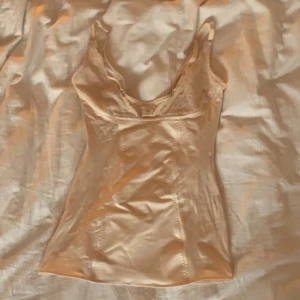 linne/korsett - gulligt linne i fint skick. storlek M men passar mer storlek S. färgen är beige/ puderrosa. Sömmarna fungerar lite korsett-aktigt!❤️