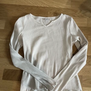 Vit långärmad tröja - Vit långärmad tröja med volanger och slit vid halsen 