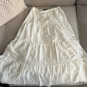 Lång vit kjol från Brandy Melville cirka 90cm lång.💓  Använd en gång. Ett par små fläckar på baksidan av kjolen (bild kan jag skicka vid behov)😊Står ingen storlek men kläder från Brandy Melville brukar säljas som onesize.  