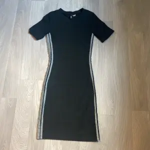 Svart figurnära klänning från H&M med reflexer längs sidorna